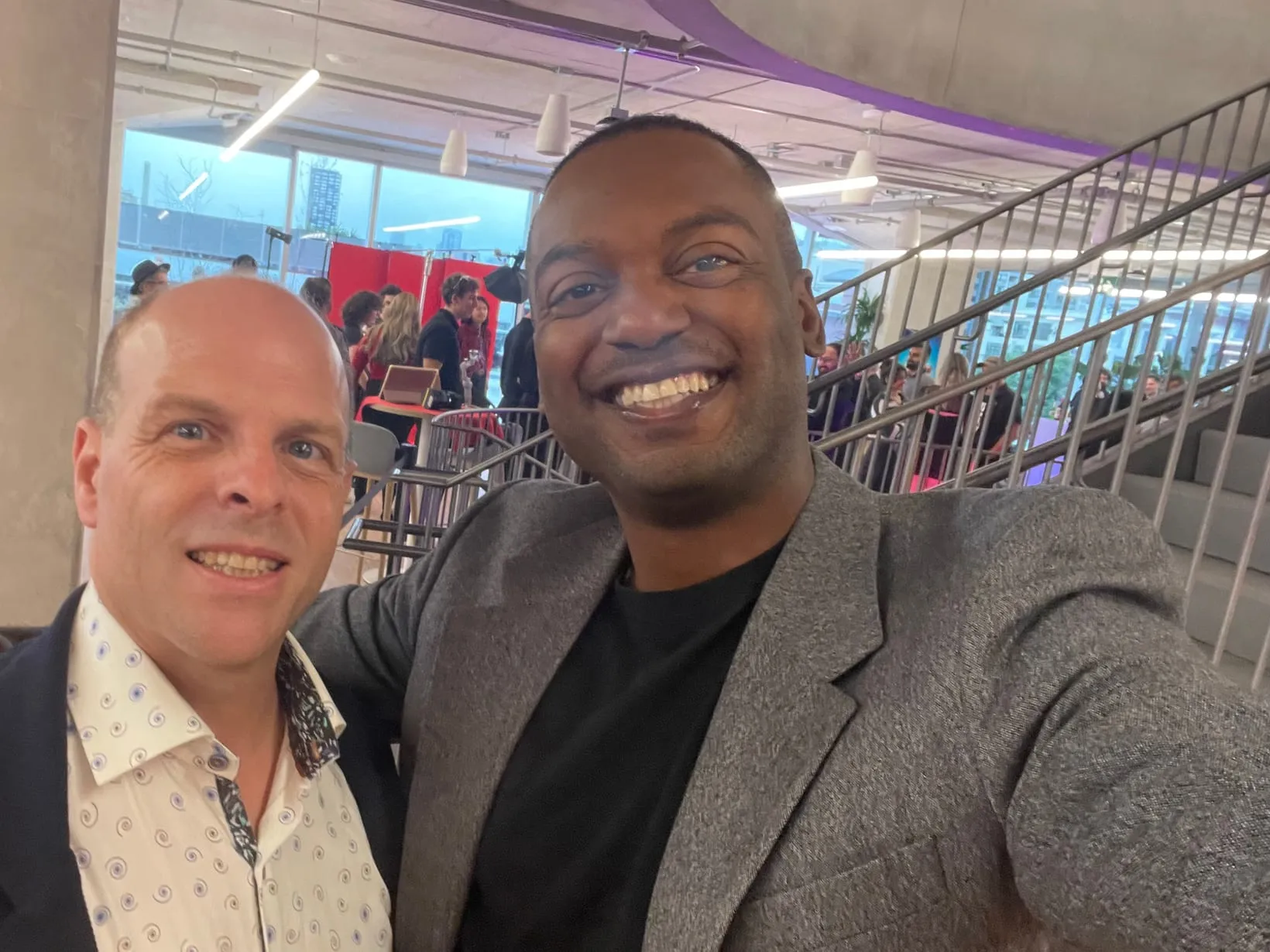 Bryce McLaughlin and Johny Duval smiling together at an indoor industry event.